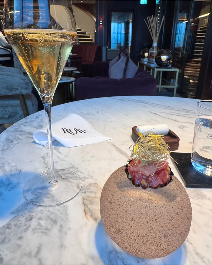 Sparkling wine and a plated appetiser on a marble table in a stylish restaurant