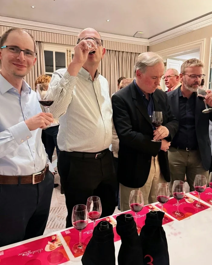 Guests taste red wine at a private tasting table with covered bottles
