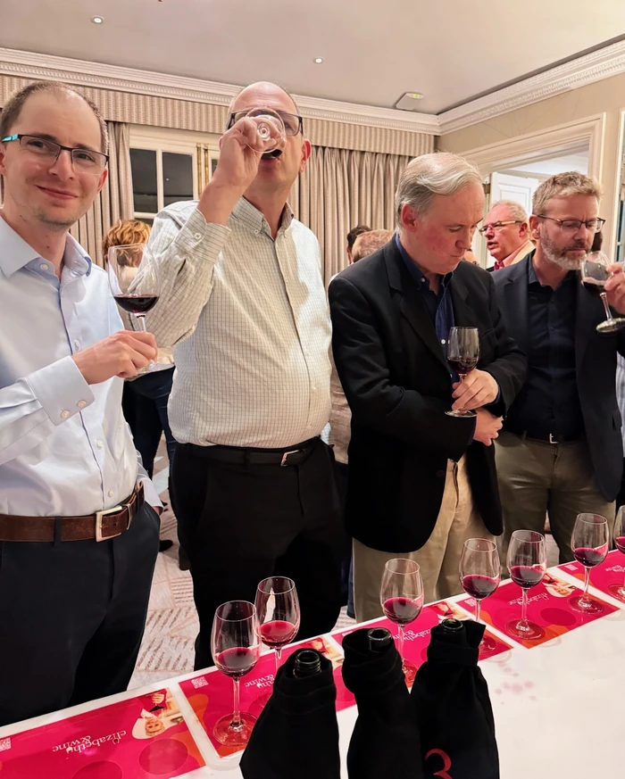 Guests taste red wine at a private tasting table with covered bottles