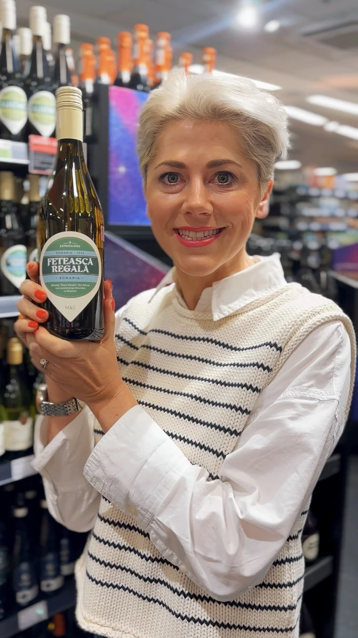 Woman holding a bottle of Fetească Regală wine in a shop