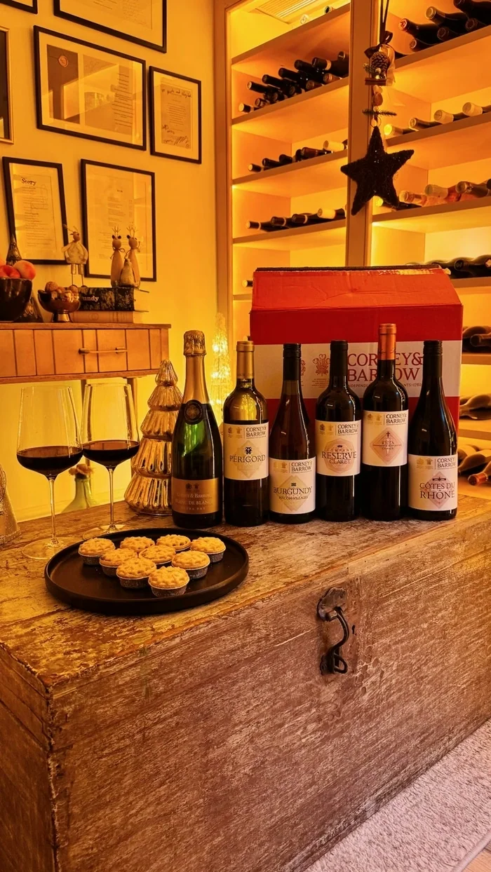 Corney & Barrow wines, glasses and mince pies arranged on a wooden table