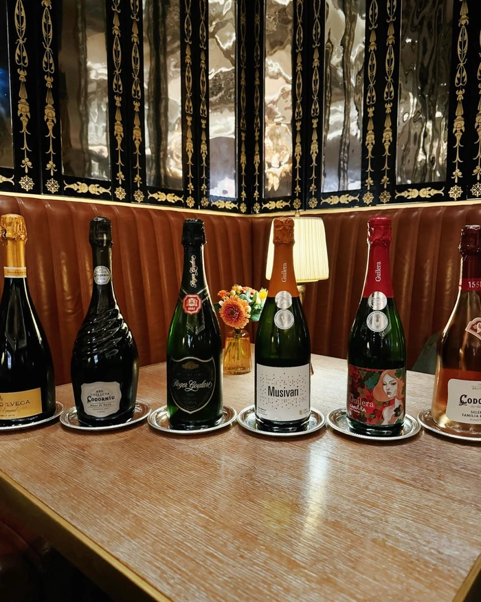 Selection of Cava bottles displayed on silver trays in a restaurant booth