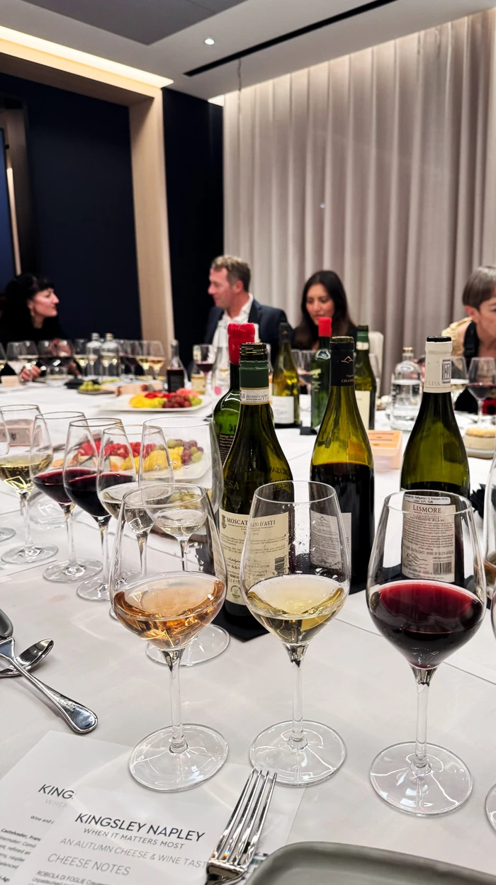 Wine tasting table with glasses, bottles, cheese plates and guests at Kingsley Napley