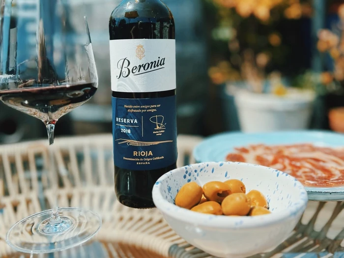 Beronia Rioja Reserva 2018 beside a glass of red wine, olives and Spanish tapas