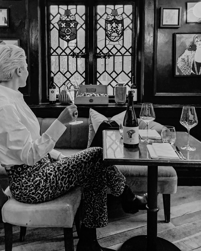 Diner holding a wine glass beside a bottle and glasses in a stylish restaurant