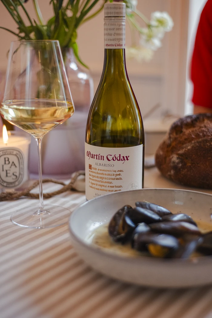 Martín Códax Albariño beside a glass of white wine and a plate of seafood