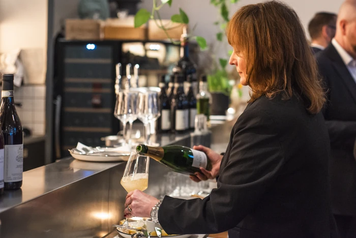 Guest pours sparkling wine into a tasting glass at a restaurant bar