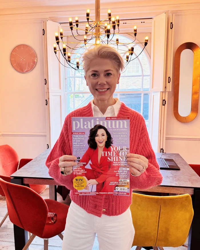 Woman holding a copy of Platinum magazine in a colourful dining room