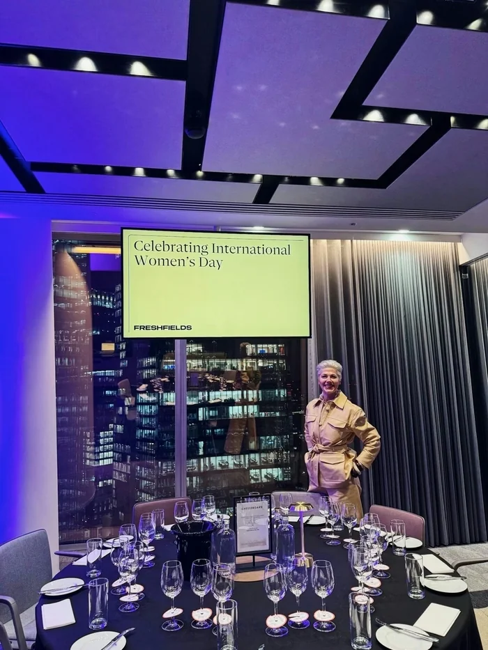 Wine tasting table set for Freshfields' International Women's Day event, with a smiling host beside it