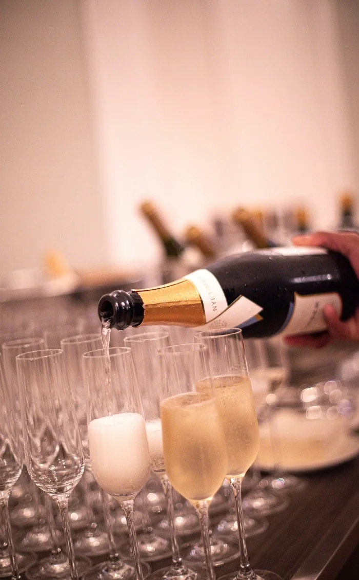 Bottle pouring sparkling wine into champagne flutes