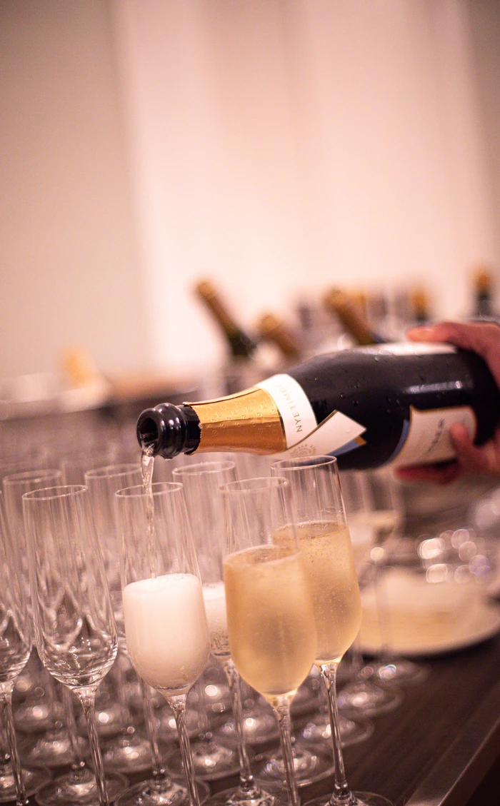 Bottle pouring sparkling wine into champagne flutes