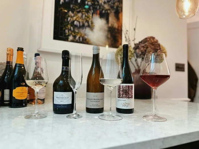 Wine bottles and glasses showing sparkling, white and red wines on a marble surface