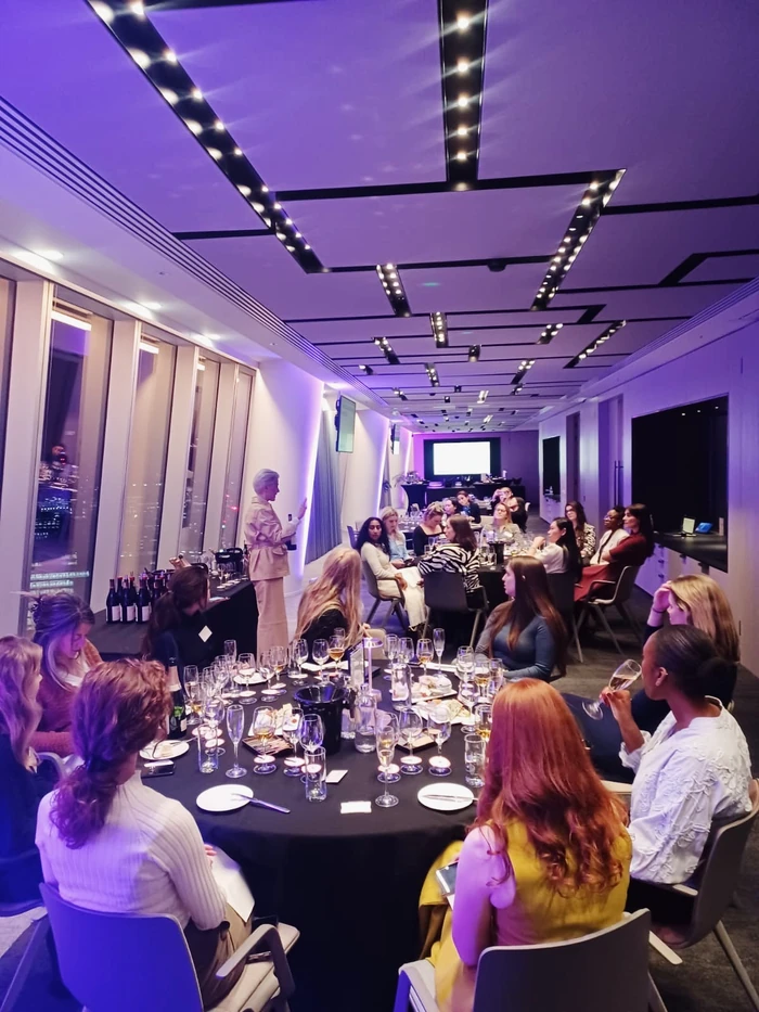 Corporate wine tasting with guests seated around a table in a purple-lit event room