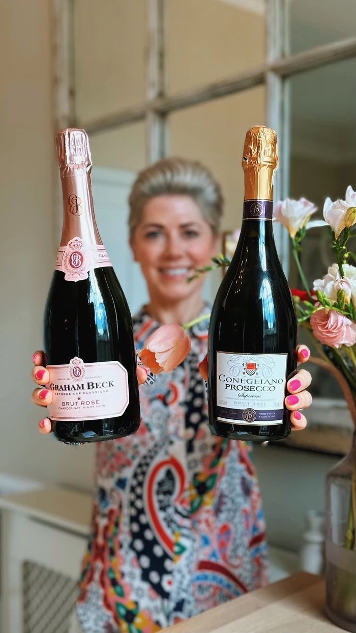 Woman holding Graham Beck Cap Classique and Conegliano Prosecco bottles
