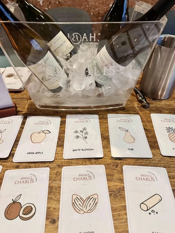 Chablis bottles chilling in ice beside tasting cards on a wooden table