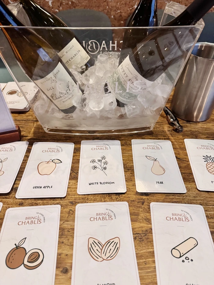 Chablis bottles chilling in ice beside tasting cards on a wooden table