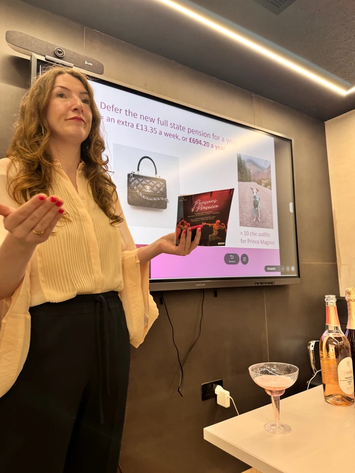 Presenter holding a Pensions & Prosecco booklet beside a presentation screen and rosé sparkling wine