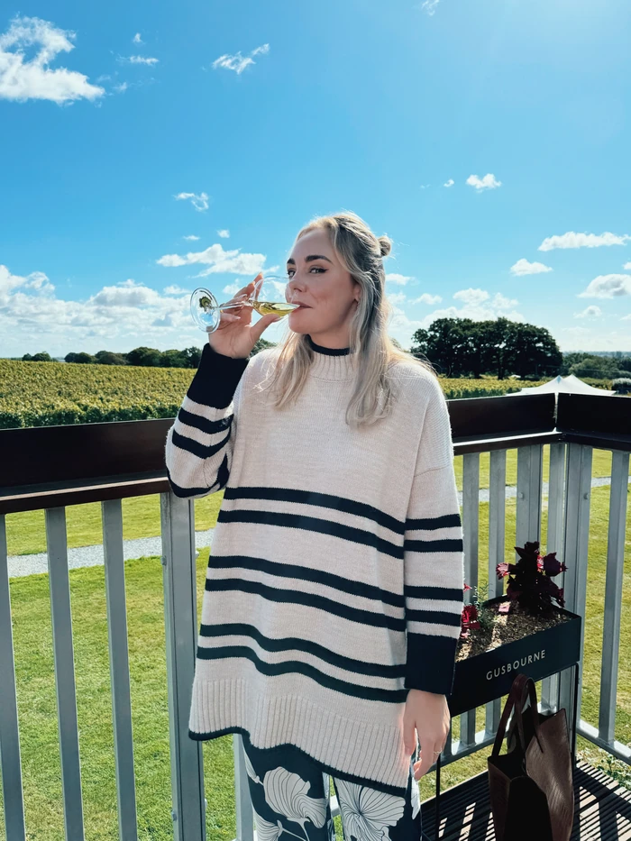 Woman tasting sparkling wine on a balcony overlooking a vineyard