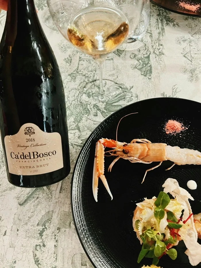 Ca' del Bosco Franciacorta with langoustine dish, wine glass and patterned tablecloth