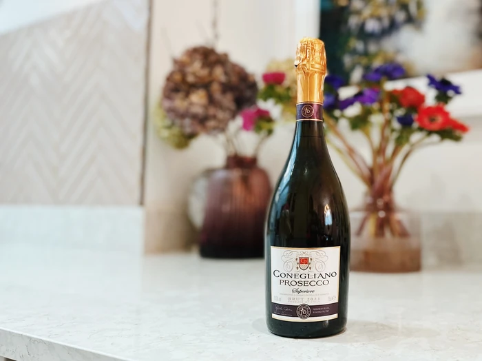 Conegliano Prosecco Superiore bottle on a marble surface with flowers behind