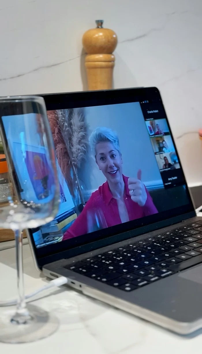Laptop showing a virtual wine tasting beside a wine glass
