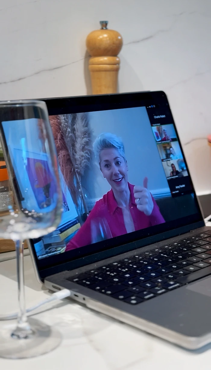 Laptop showing a virtual wine tasting beside a wine glass