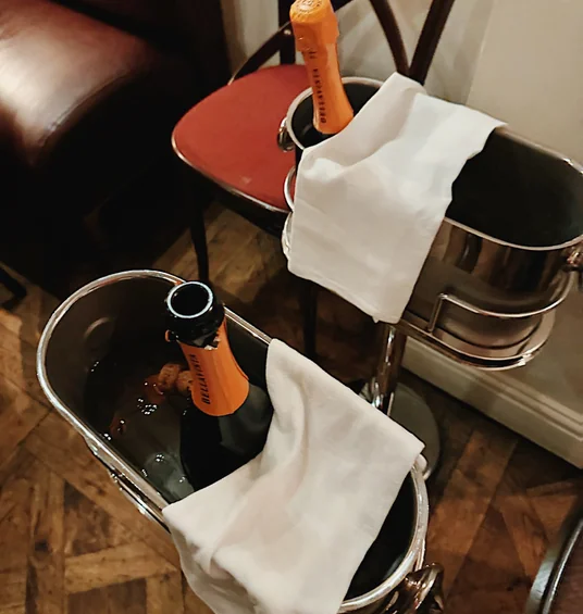 Wine bottles chilling in silver ice buckets beside a red chair