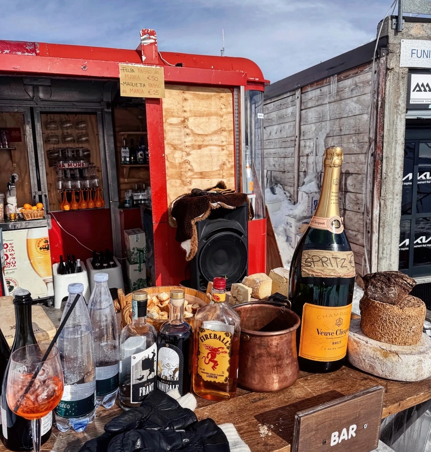 Outdoor mountain bar serving cocktails, sparkling wine, spirits and cheese beside a snowy ski area