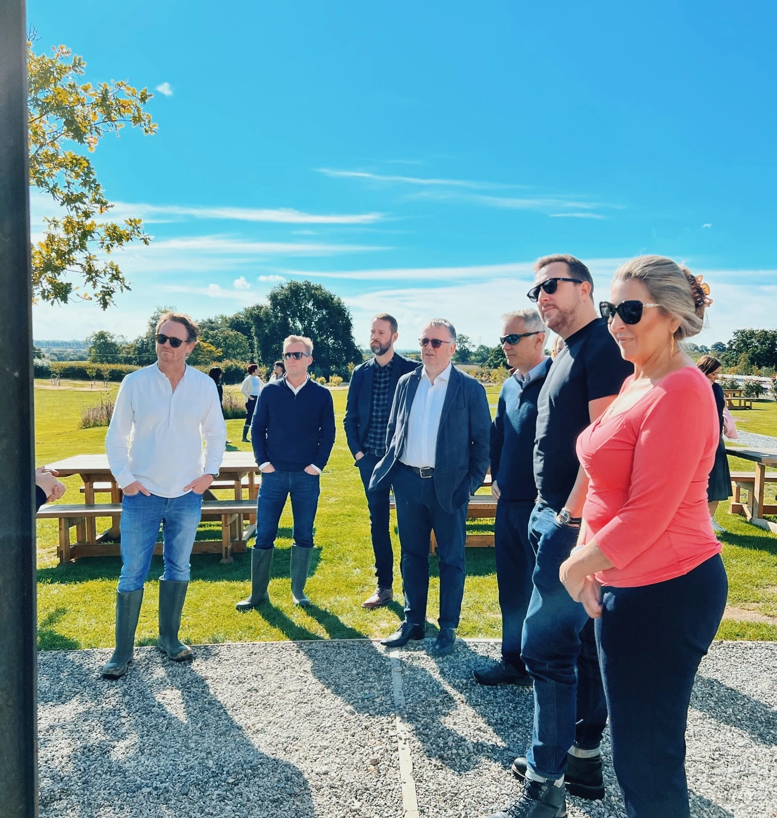 Group standing outside a winery beside vineyard rows on a sunny day