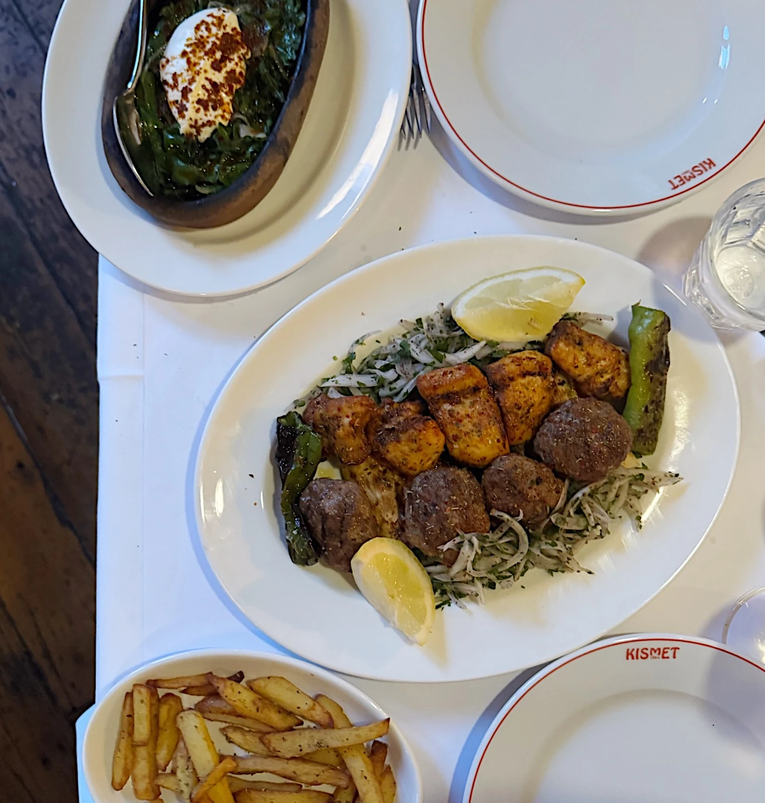 Kismet restaurant table with grilled meat, vegetables, dip and chips