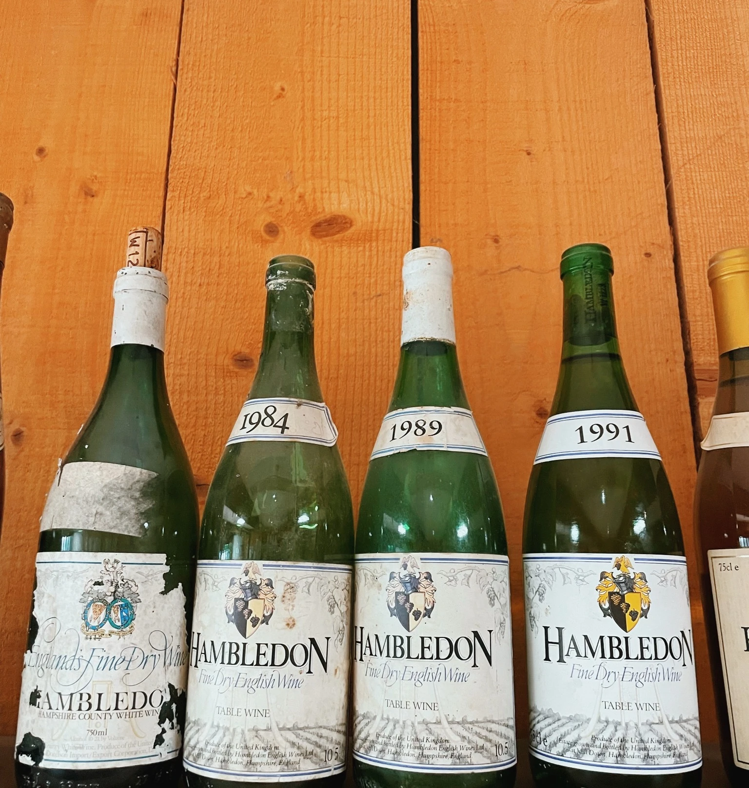 Vintage Hambledon English wine bottles labelled 1984, 1989 and 1991 on a wooden shelf