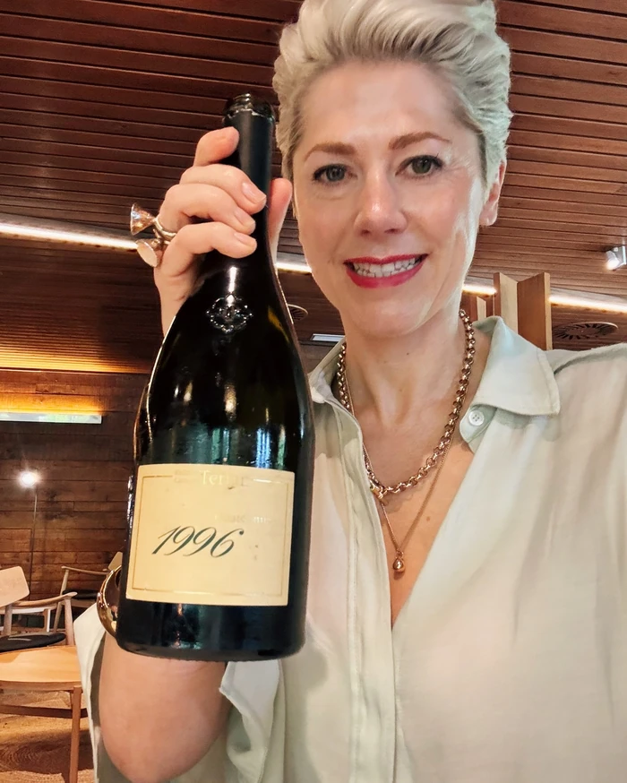 Woman holding a 1996 wine bottle in a restaurant