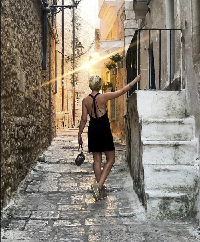 Woman in black dress walking through a narrow stone alley