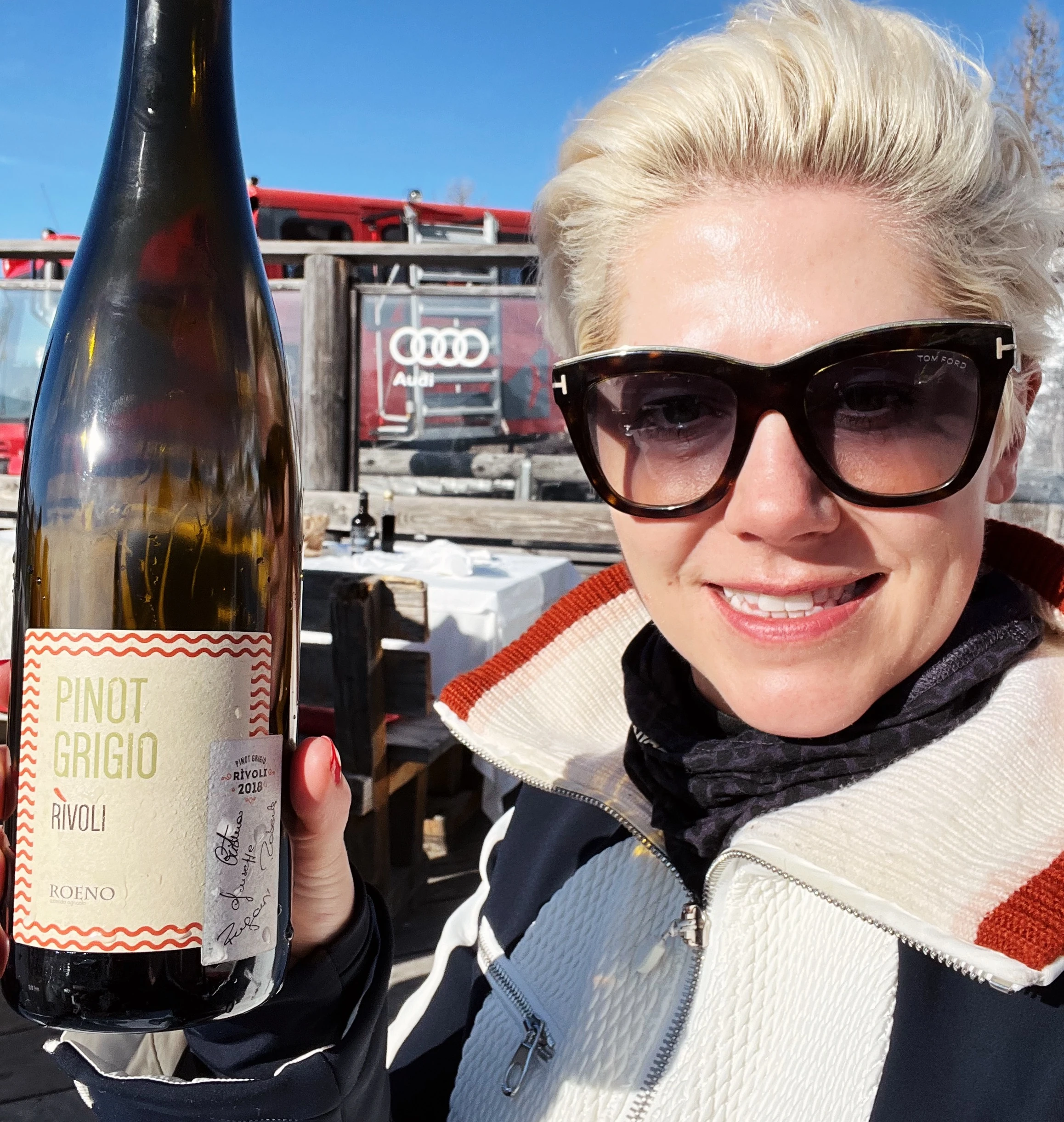 Elizabeth holds a bottle of Pinot Grigio Rivoli wine outdoors in the Dolomites