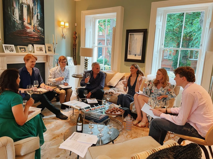 Wine tasting group in elegant living room with glasses and notes