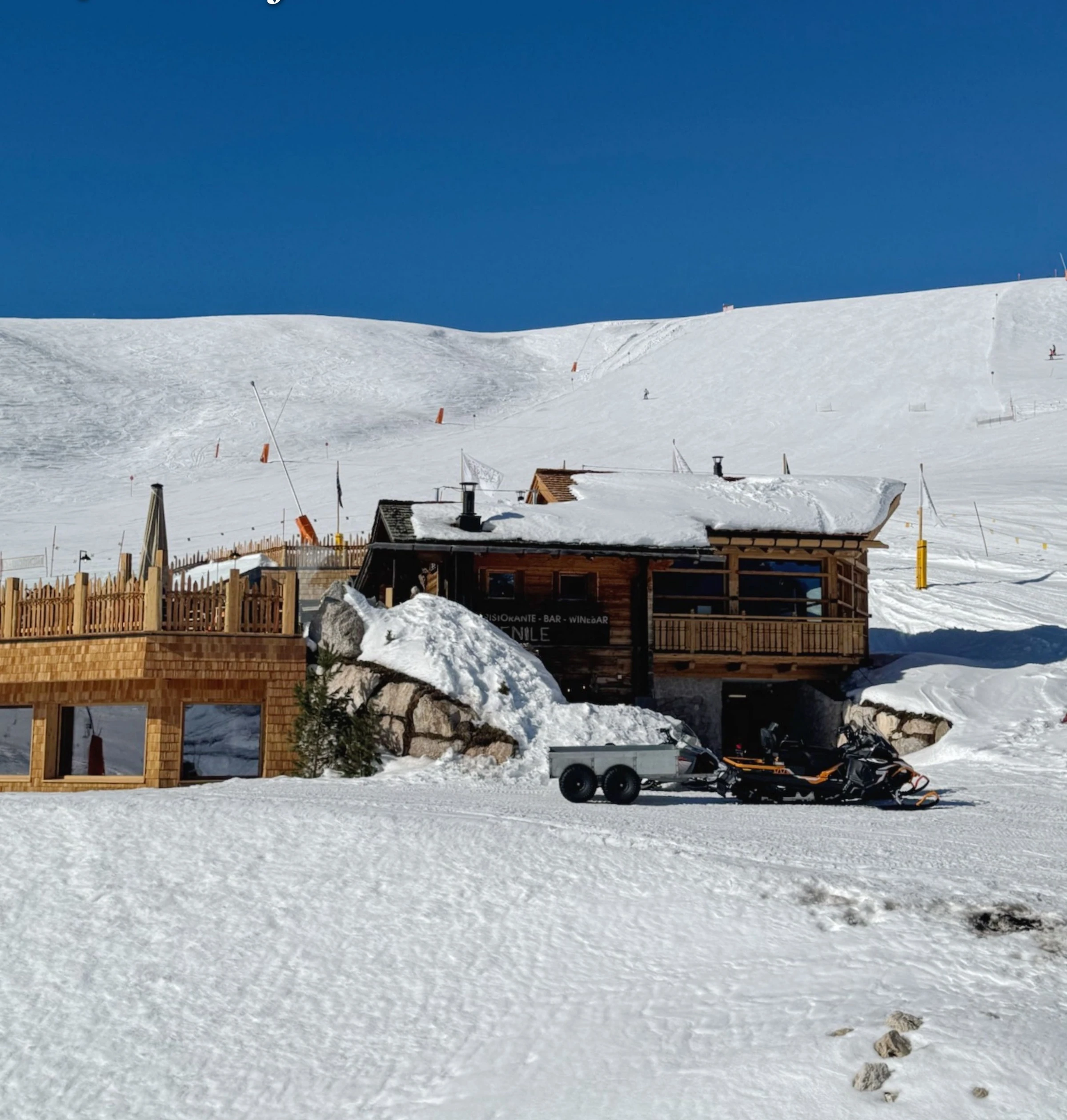 Snow-covered Fienile steak restaurant beside a ski slope in the Dolomites