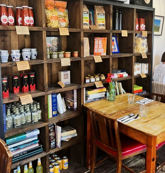 Italian deli shelves stocked with pasta, sauces, drinks and cookbooks beside a set dining table