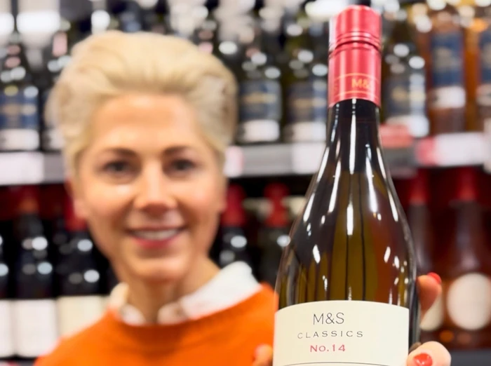 Woman holding M&S Classics wine bottle in shop aisle