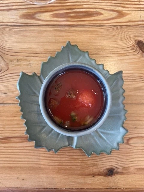 Cup of red cocktail on leaf-shaped plate on wooden table