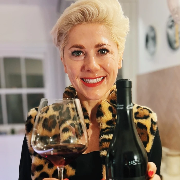 Woman holding red wine glass and bottle indoors