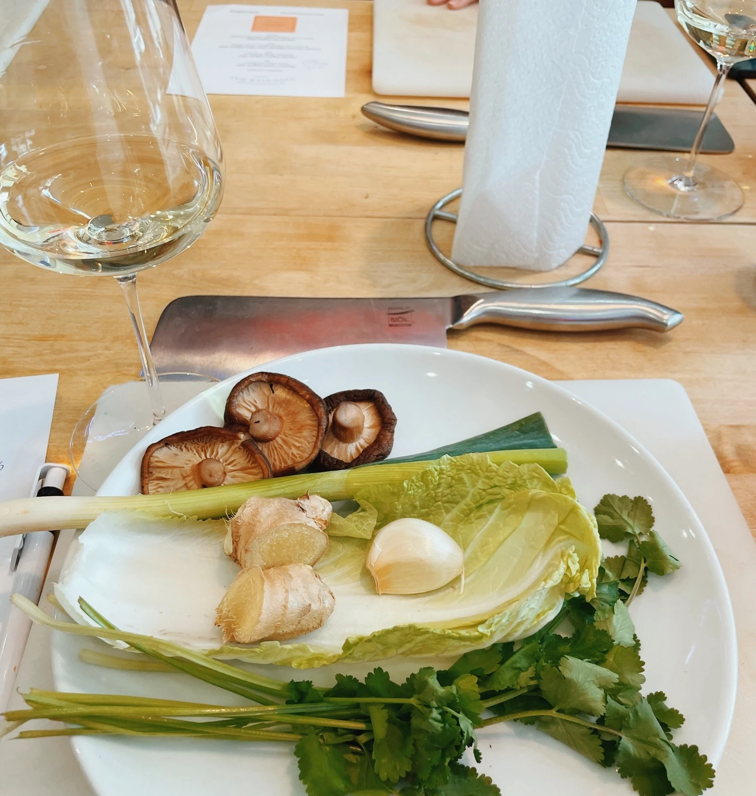 Ingredients for a wine and food tasting beside glasses of white wine and a chef's knife