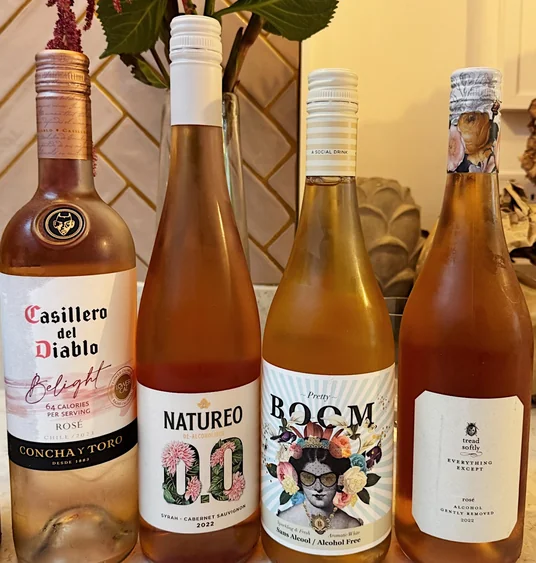 Four bottles of rosé and alcohol-free wine displayed beneath a vase of flowers