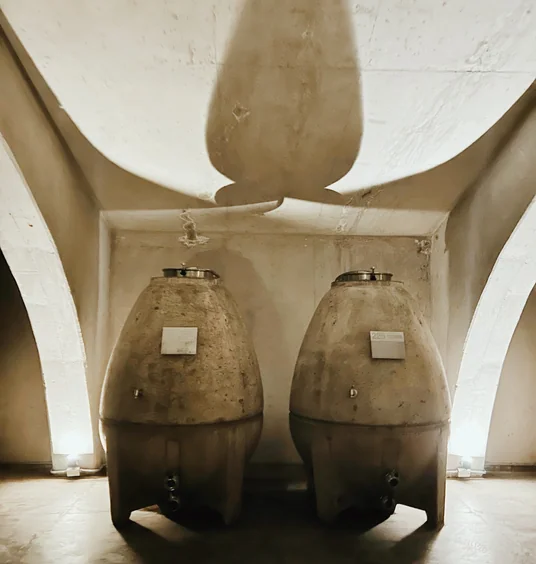 Two large ceramic wine vessels beneath an arched cellar ceiling