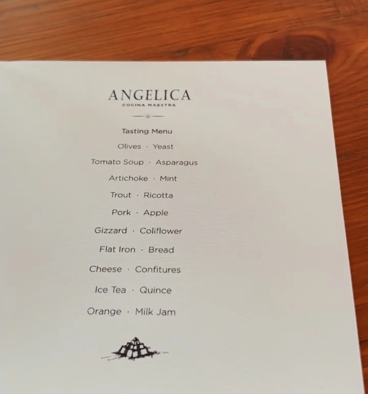 Angelica tasting menu beside wine glasses on a wooden table