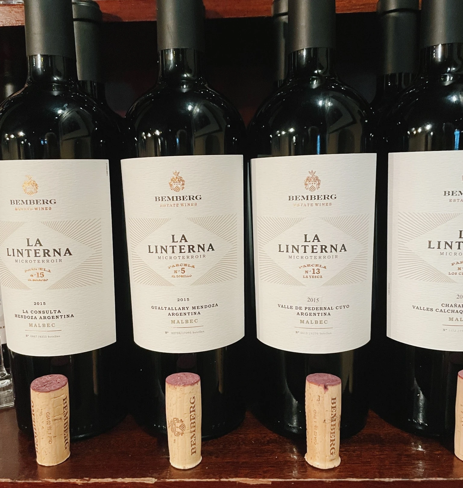 Bemberg La Linterna Malbec wine bottles arranged with their corks on a wooden shelf