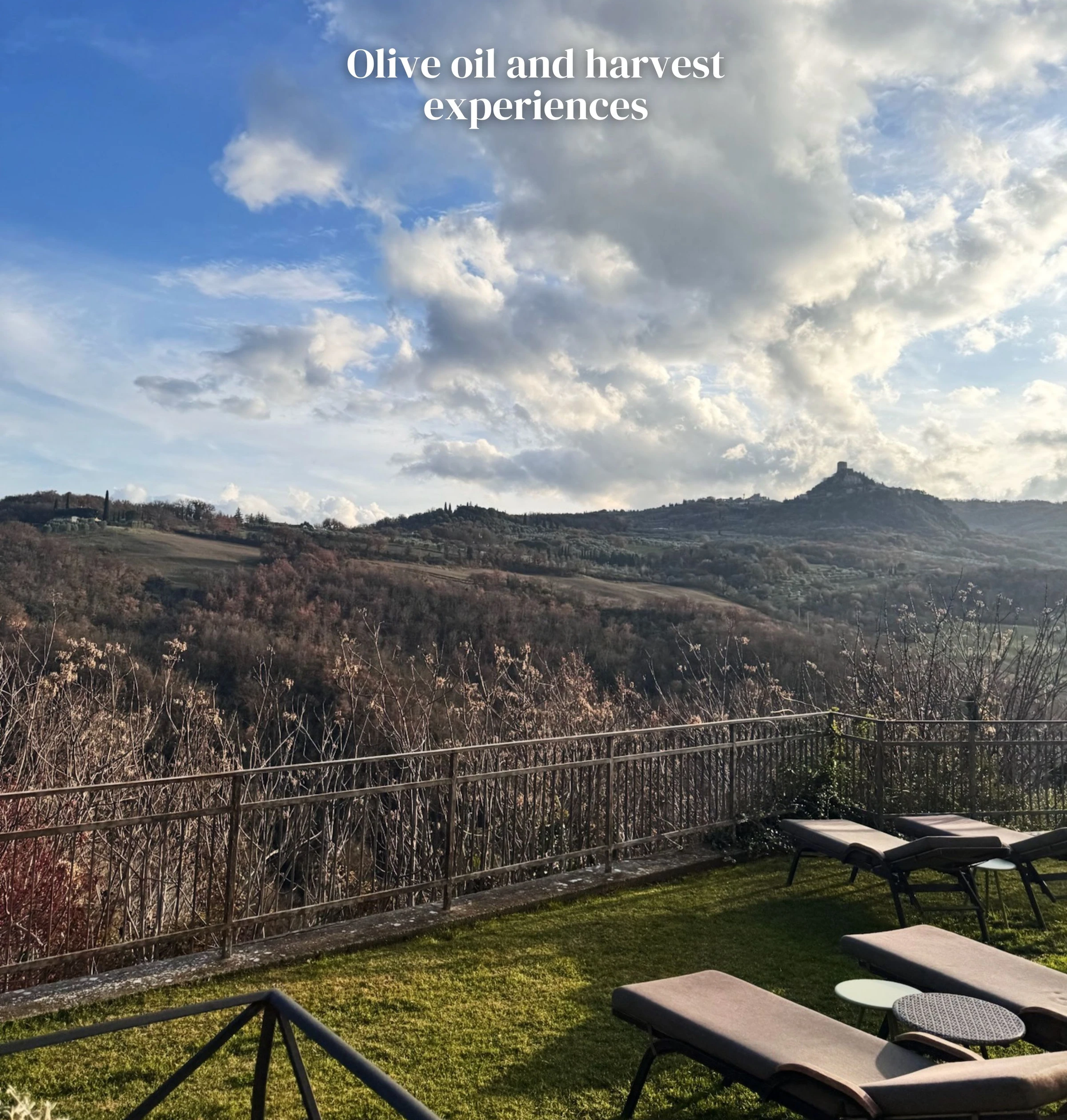 Tuscan countryside viewed from a lawn with loungers beneath a dramatic cloudy sky