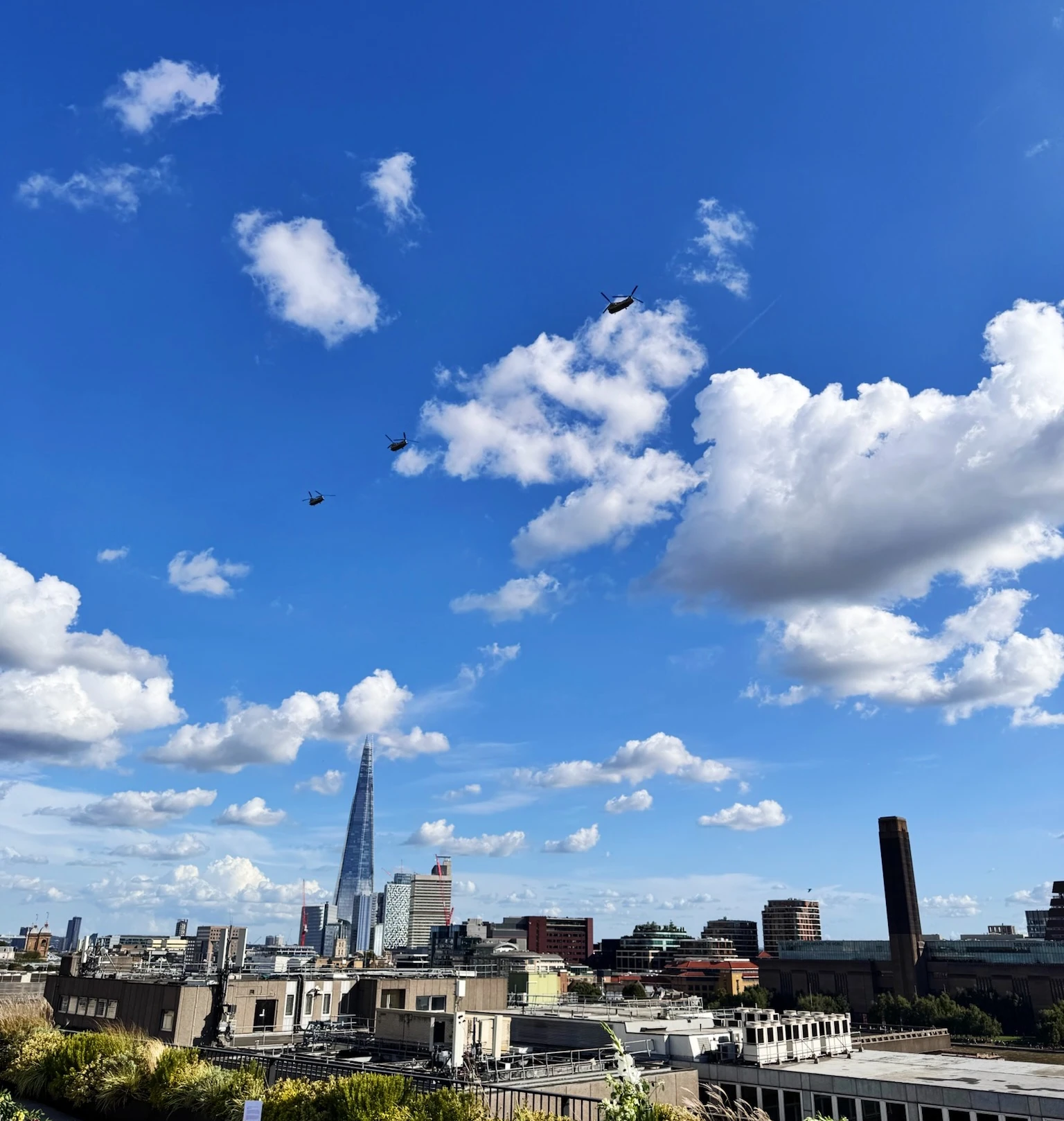 Rooftop terrace with The Shard, city buildings and helicopters beneath a blue sky