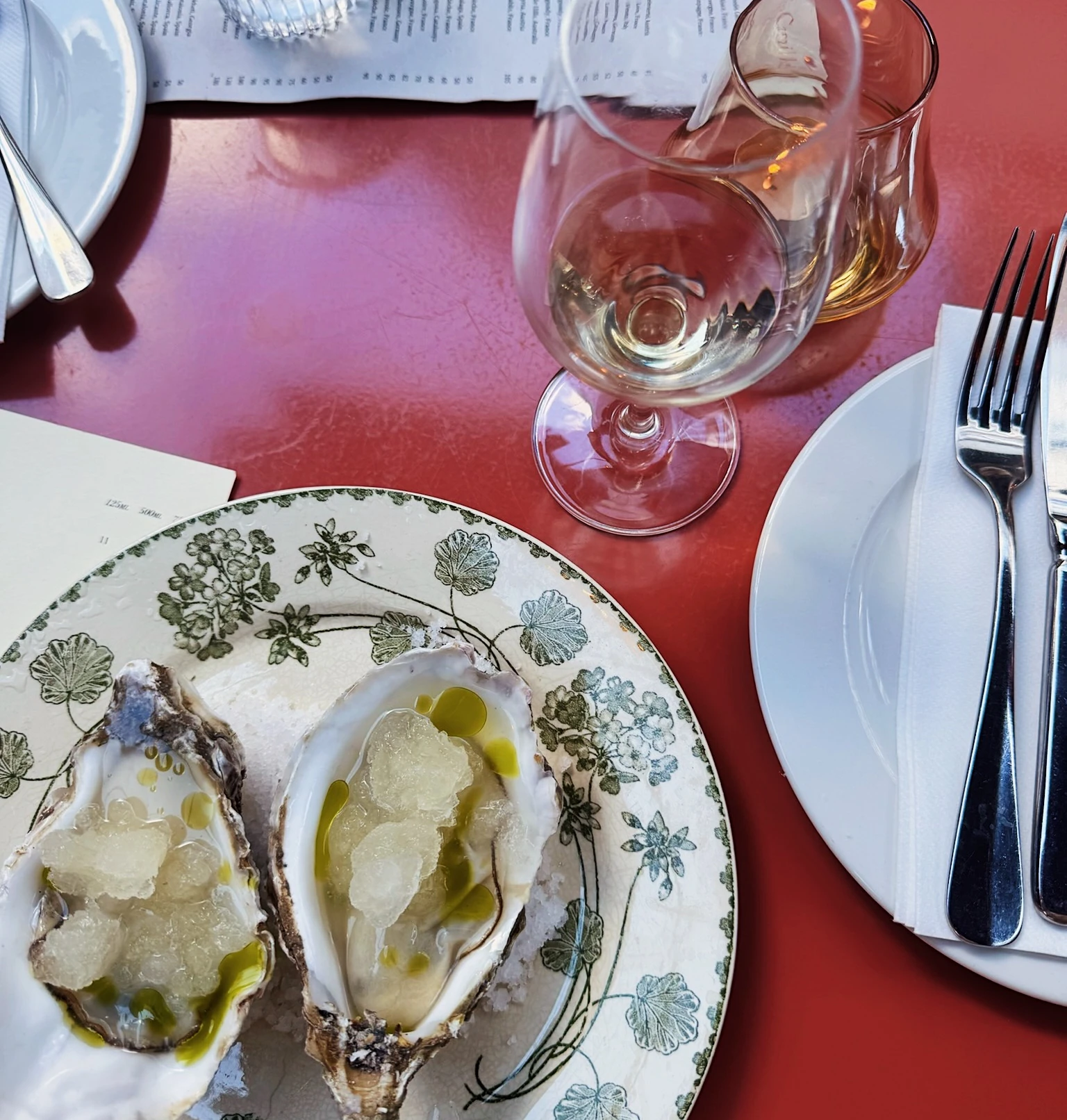 Oysters on ice beside wine glasses and a formally laid table