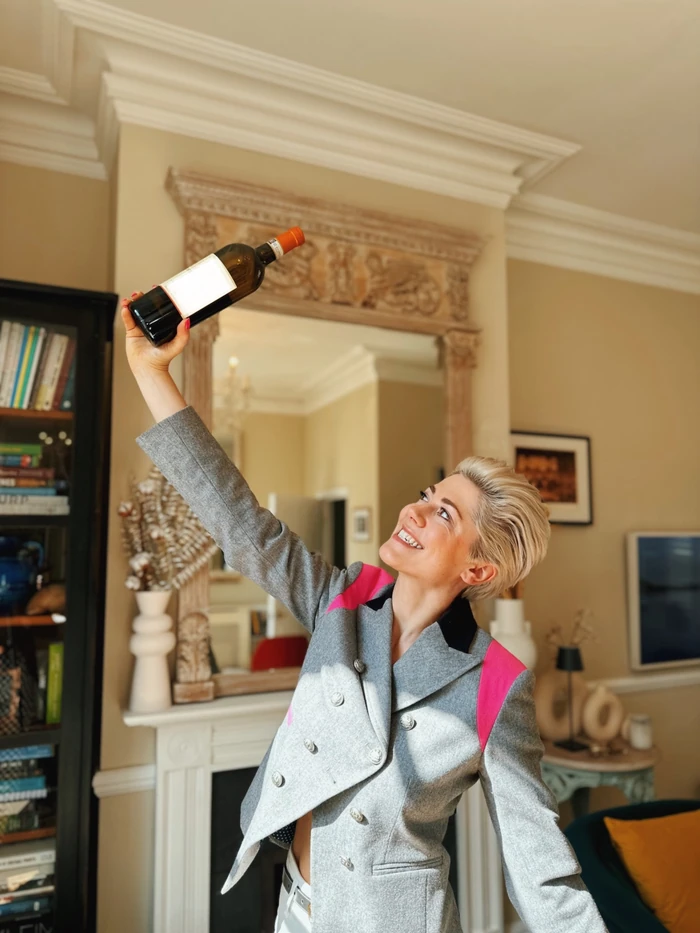 Woman holding up wine bottle in elegant living room