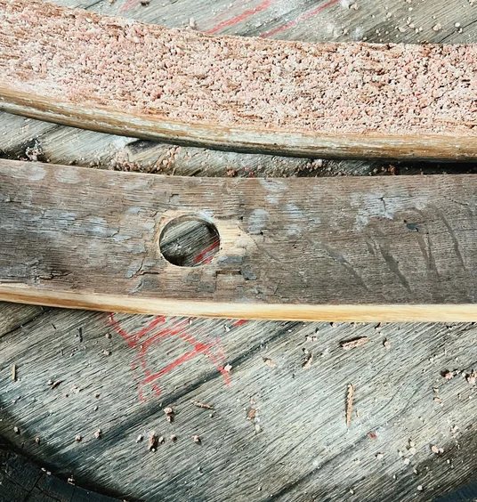 Close-up of a wooden Champagne barrel with a circular bung hole and pink grape residue